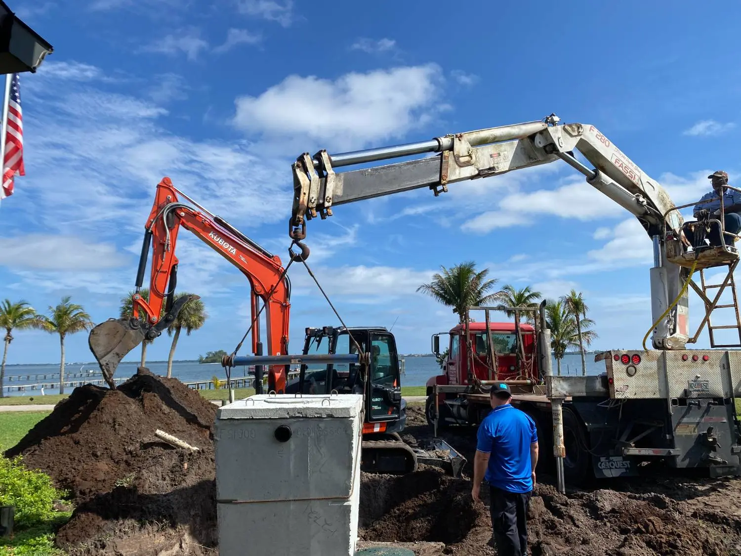 Crotty Services crew setting a concrete septic tank with a crane and excavator