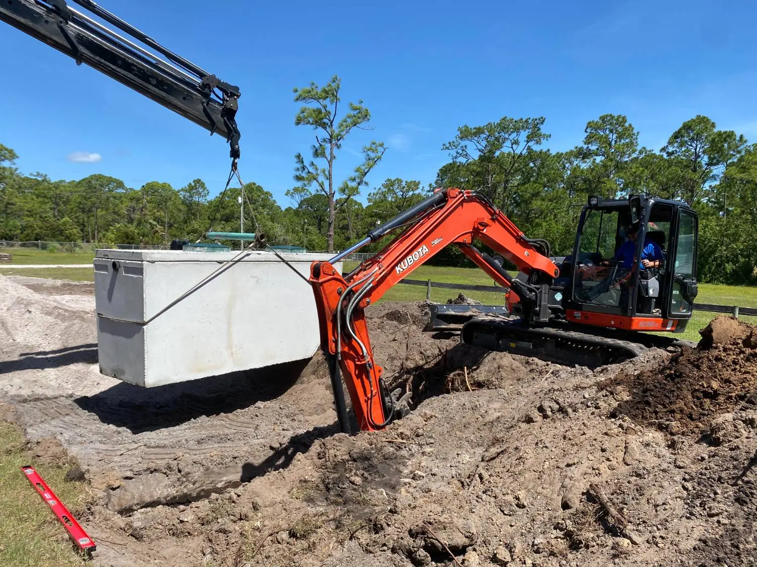 Crew lowering a new septic tank into place