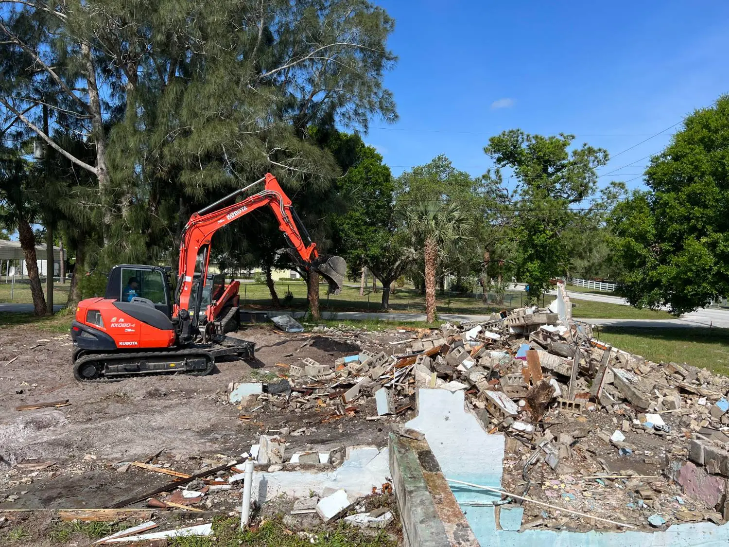 Excavator clearing land beside a gravel road